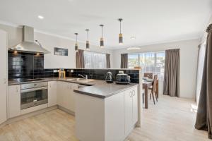 a kitchen with white cabinets and a counter top at Hunia Haven - Himatangi Beach Holiday Home in Oroua Downs