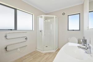 a white bathroom with a shower and a sink at Hunia Haven - Himatangi Beach Holiday Home in Oroua Downs +11 photos