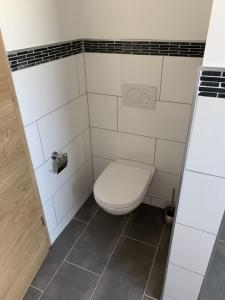 a bathroom with a toilet in a white tiled room at Auf dem Rheinsteig in Lierschied