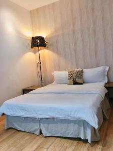 a bedroom with a large white bed with a lamp at in墾丁 in Kenting