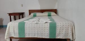 a bed with a green and white comforter on it at Centro Ecoturistico Ya´ajche in Lacanjá
