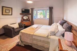 a bedroom with a bed and a chair and a window at Heritage Cottage Margaret River in Margaret River Town