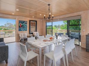 a dining room with a table and white chairs at All Decked Out - Matarangi Holiday Home in Matarangi