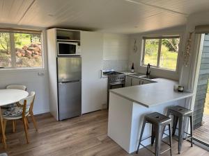 una cucina con bancone, tavolo e sedie di 125 Church Bay Cabins a Oneroa