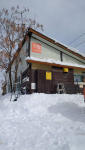 un bâtiment avec de la neige devant lui dans l'établissement HAKUBA IKEDA LIFE KAN APARTMENTS, à Hakuba