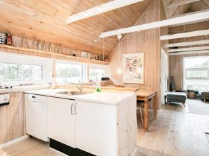 Kandestederneにある7 person holiday home in Skagenの白いキャビネットと木製の天井が備わるキッチン