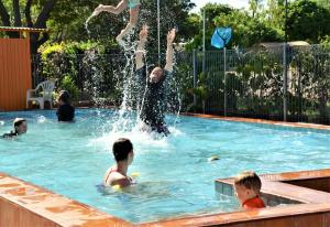 un grupo de personas en una piscina jugando en el agua en Affordable Gold City Motel, en Charters Towers