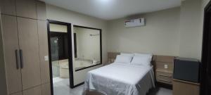 a bedroom with a bed and a bathroom with a tub at Casa nos Ingleses com piscina e jacuzzi in Florianópolis