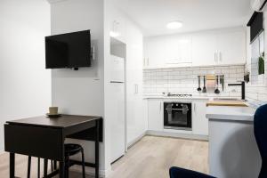 une cuisine avec des placards blancs et un comptoir noir dans l'établissement Bayswaterfront Apartments, à Adélaïde