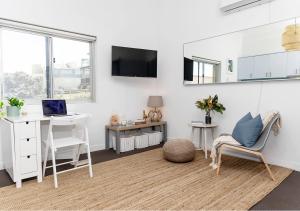 a white room with a desk and a laptop and a chair at COZY BEACH FRONT STUDIO WITH AIRCON in Sydney