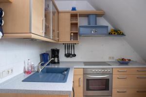 a kitchen with a sink and a stove and cabinets at Ferienwohnung Smieszek in Niesky