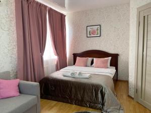 クラスノダールにあるВид на стадион Краснодарのベッドルーム1室(ピンクの枕と椅子付きのベッド1台付)