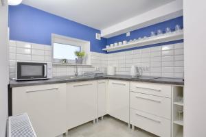 eine Küche mit weißen Schränken und einer blauen Wand in der Unterkunft Apartament Niebieski in Klein Öls