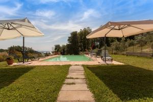 a swimming pool with two umbrellas and chairs at Agriturismo La Gismonda in Bracciano
