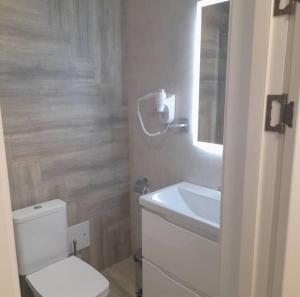 a bathroom with a white toilet and a sink at Kaspi Hotel in Oral