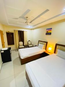 a hotel room with two beds and a tv at Plaza Inn Hotel in Rahimyar Khan