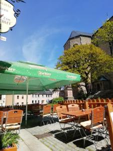 a group of chairs and tables with a green umbrella at Gaststätte & Pension Zum Türmer in Annaberg-Buchholz