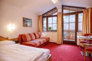 Habitación de hotel con cama, sofá y ventana en Feriendorf Ponyhof, en Fusch an der Glocknerstrasse