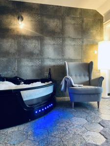 een badkamer met een bad, een stoel en een bank bij Ludwig Hotel in Martonvásár
