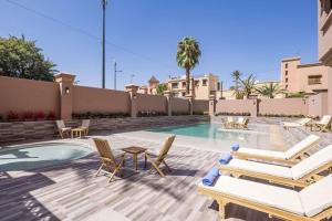 Hotel Ayoub & Spa في مراكش: فناء مع كراسي ومسبح مع طاولة