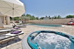 a hot tub with chairs and an umbrella next to a pool at Casa Siesta in Murine