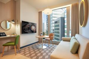 a hotel room with a couch and a table and a window at Citadines Raffles Place Singapore in Singapore