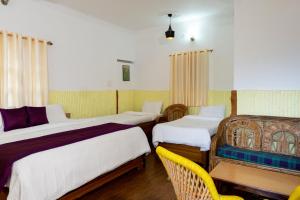 pokój hotelowy z 2 łóżkami i żółtym krzesłem w obiekcie Tarana Cottage by Namastexplorer w mieście Bhowāli