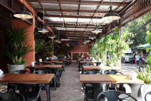 a restaurant with wooden tables and chairs and plants at Rambuttri Village Plaza in Bangkok