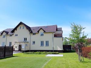 a large white house with a fence at Apartmán Jeseníky in Karlovice