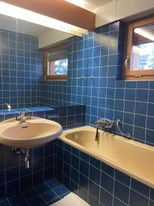 ein blau gefliestes Bad mit einem Waschbecken und einer Badewanne in der Unterkunft Rose des Alpes in Leysin
