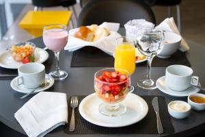 a table with a bowl of fruit and glasses of juice at Le CanarD Joinville in Joinville