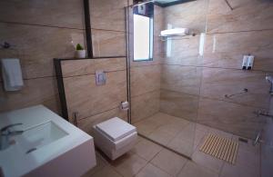 a bathroom with a shower and a toilet and a sink at Sai Maa Hotel & Residency in Puttaparthi