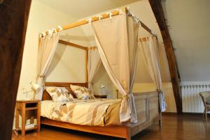 a bedroom with a canopy bed with curtains at Le Tulipier de Virginie in Noyers-sur-Cher