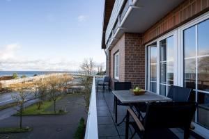 einen Balkon mit einem Tisch, Stühlen und Meerblick in der Unterkunft Seepark Wohnung 2 1 in Scharbeutz