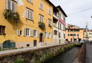 a yellow building next to a river with buildings at Casa Janca, Find sanctuary at extraordinary rates! Luxury Smart Apartment in Central Lucca in Lucca