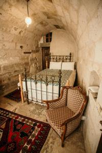 a bedroom with a bed and a chair in a stone room at Village Cave House Hotel in Göreme