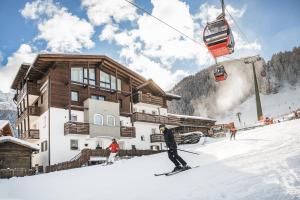 塞爾瓦迪瓦爾加爾德納的住宿－Garni Hotel Miara - Your Dolomites Home，滑雪者在滑雪缆车前的雪中滑雪