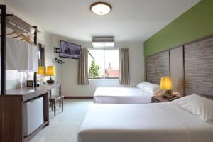 a hotel room with two beds and a television at Rambuttri Village Plaza in Bangkok