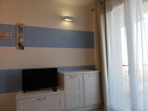 a room with a television on a cabinet with a window at Suite Smeralda sea view in Castelsardo