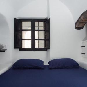 a bedroom with a blue bed and a window at Villa Orpheus Santorini in Megalokhori