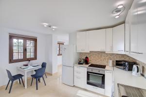 une cuisine avec des armoires blanches et une table et des chaises dans l'établissement Apartamentos Los Enanos La Palma, à Santa Cruz de la Palma