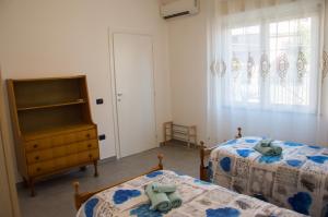 1 Schlafzimmer mit 2 Betten, einer Kommode und einem Fenster in der Unterkunft Casa jole in Assemini