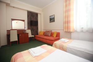 a hotel room with two beds and a red couch at Restauracja Noclegi Ruczaj in Nowy Targ