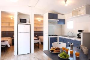 a kitchen with blue cabinets and a table with food on it at Camping Bella Austria in Sankt Peter am Kammersberg