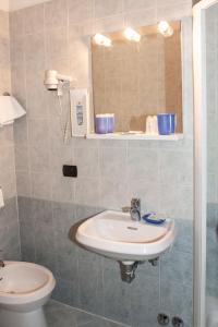 a bathroom with a sink and a toilet and a mirror at Hotel Melecchi in Lucca