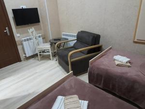a room with two beds and a chair and a tv at AnSeZa in Kutaisi