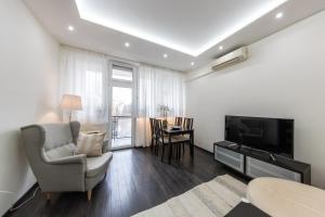 a living room with a television and a chair and a table at Spacious 3-room apartment with free parking in Budapest