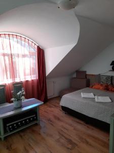 a bedroom with a bed and a couch and a window at Zöld Sziget Vendégház in Eger