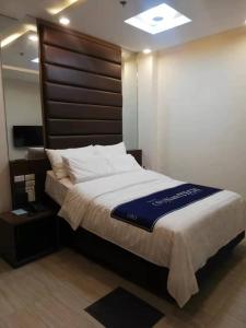 Schlafzimmer mit einem großen Bett mit einem Kopfteil aus Holz in der Unterkunft NutriTECH Hotels & Events in Calapan
