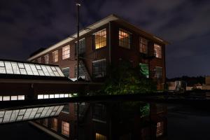 een gebouw met zijn reflectie in het water 's nachts bij Hotel Piet Hein Eek in Eindhoven